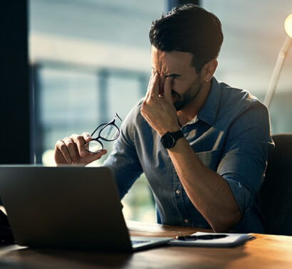 Struggling with computer problems causing more stress. Shot of a young businessman experiencing stress during a late night at work