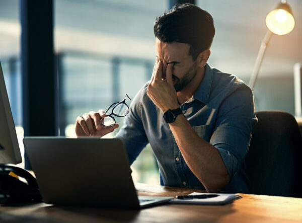 Struggling with computer problems causing more stress. Shot of a young businessman experiencing stress during a late night at work